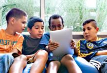 四个男孩坐在豆袋上盯着平板电脑屏幕